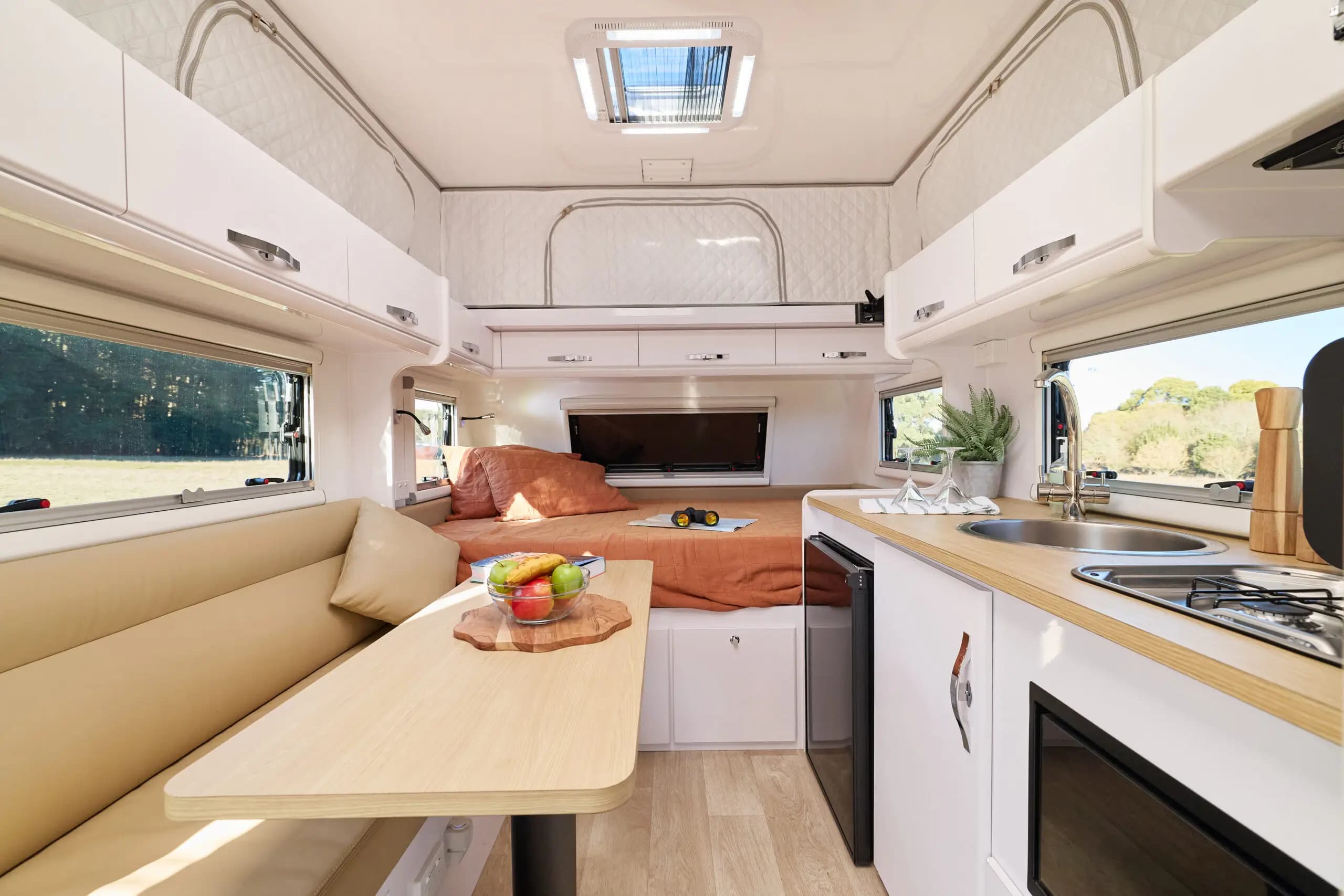 Pop top caravan interior with bed, kitchen, and dining area